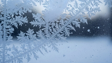 Intricate frost patterns on a window pane in winter