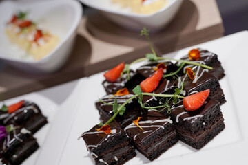 Close up of double layer dark chocolate brownie squares with glossy ganache, strawberry
