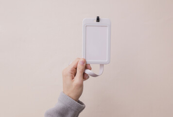 White bkank id badge in hand of woman wearing a fleece sweatshirt. Trainer, gym instructor, sports and fitness concept, mockup. © VI-stock studio