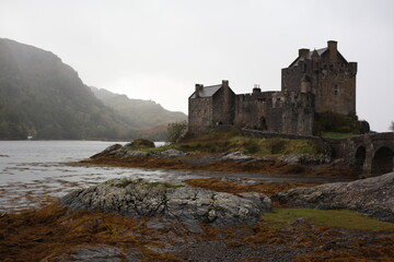 Fototapeta premium Eilean Donan Castle in Scotland, a historic medieval fortress perched on island, connected by a stone bridge and surrounded by scenic loch and hills.