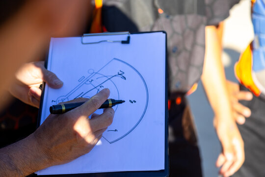 Coach drawing game strategy on clipboard - Powered by Adobe