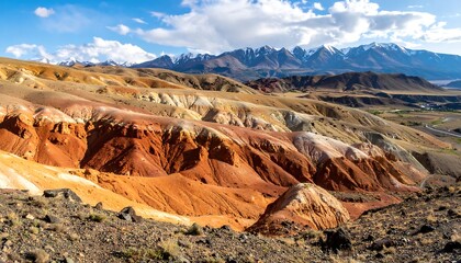 A sweeping landscape with vibrant multi-colored earth formations, contrasted against snow-capped peaks under a bright blue sky