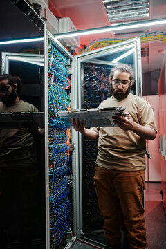 Young IT engineer examining machine part working in server room