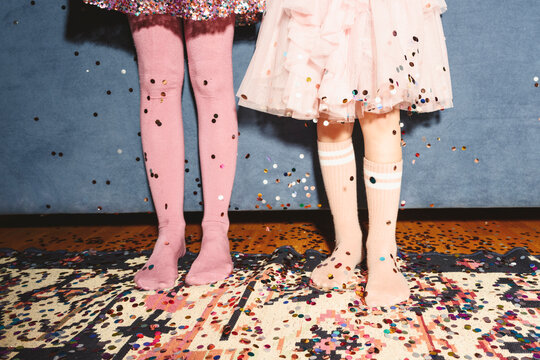 Legs of girls standing on floor covered with confetti