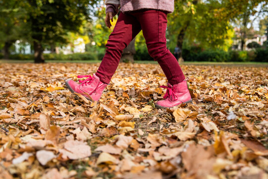 Girl walking on dry leaves in autumn park