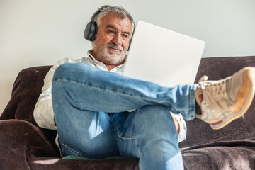 Senior man relaxing at home listening to music