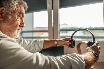 Elderly man holding headphones enjoying music and leisure at home