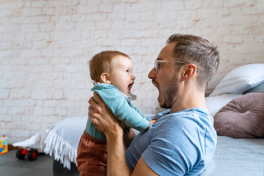 Playful father screaming with baby boy at home