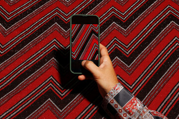 Hand of man with smartphone taking photo of abstract design