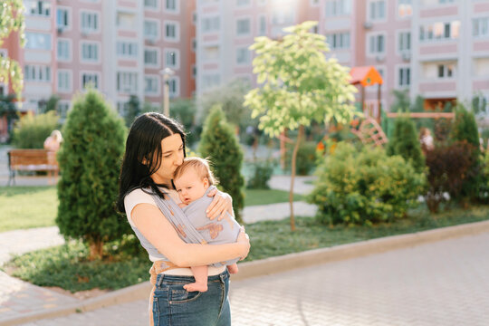 Mother kissing daughter in baby sling