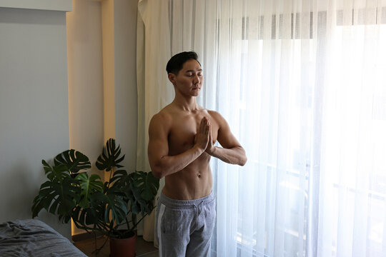 Shirtless young man meditating at home
