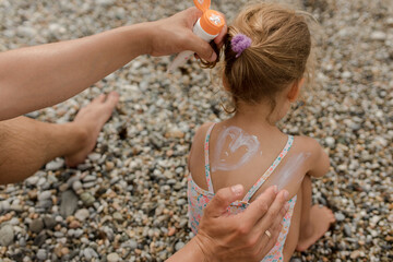 Hands of father applying suntan lotion on daughter