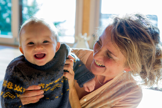 Portrait of laughing baby boy holding by his mother