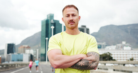 Confident, fitness and portrait of man in city with crossed arms for exercise, training and workout. Runner, athlete and person in urban town for marathon, challenge and running for health outdoor