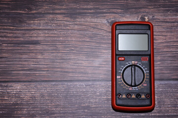 Digital multimeter on a wooden background. Electrical equipment for measuring electrical current. Energy power checker, volts, amperes