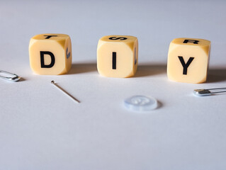 diy do it yourself sewing concept with needle safety pins and button on white background