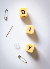 vertical diy sewing concept with needle safety pins and button on minimalist white background