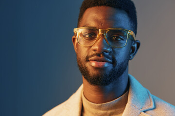 Portrait of a stylish young Black man wearing glasses and a turtleneck in a modern setting with a calm blue and orange background, conveying confidence