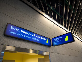 Sign above veterinary inspection office at airport. Checking and declaring pets during air travel. Concept of pet travel and transportation difficulties. Veterinary Control sign in three languages