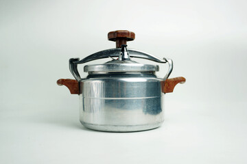 Close-up of the lid mechanism of a vintage metallic pressure cooker, showcasing the wooden handle...