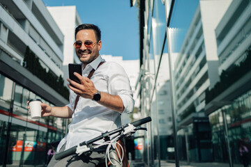 Businessman enjoying coffee and smartphone on city bike commute