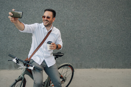 Happy man taking selfie on bike with coffee