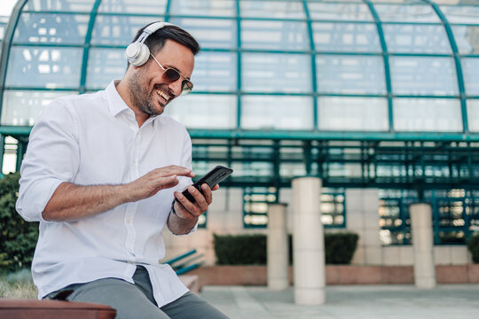 Happy man enjoying music using smartphone outdoors