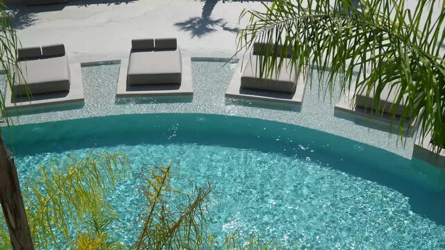 Luxury resort pool with turquoise water, modern loungers, palm fronds, and mosaic tile deck creating a serene, relaxing atmosphere for vacation getaway