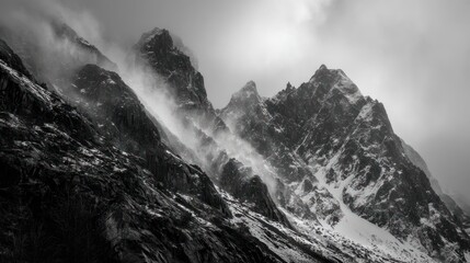 Obraz premium Dramatic monochrome mountain peaks shrouded in mist and light snow, stark, imposing