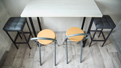 A compact table with stylish black upholstered chairs and stools in the kitchen, interior