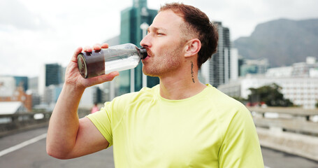 Man, fitness and drinking with water bottle in city for workout break, rest or recovery. Active, male person or runner with mineral liquid, aqua or beverage for sports hydration in an urban town