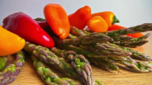 Fresh asparagus and mini sweet peppers on a wooden surface healthy vegan diet vegetables