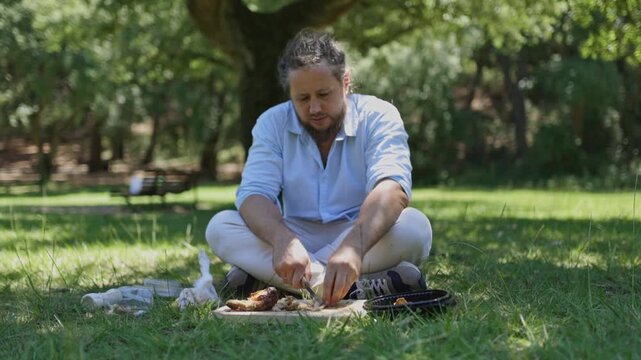 Man slicing meat and vegetables during picnic in the park