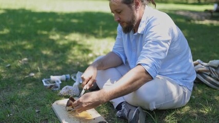 Man slicing meat for a picnic lunch