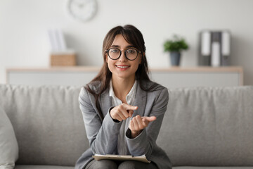 A positive middle eastern female psychologist speaks to the camera while taking notes in her cozy...
