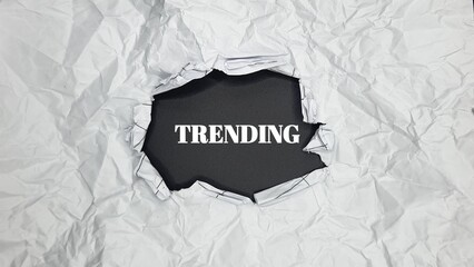 "Trending" text revealed through ripped, crumpled paper. 
