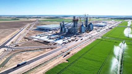 Aerial view of agricultural processing complex under construction, with fields and infrastructure