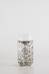 Chia seeds stirred into a glass of water on a white background