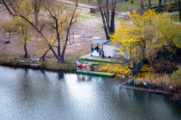 Group of brave men prepare for winter swimming or cold water bathing by a river in an autumnal park. A scene of resilience, health, and connection with nature amidst vibrant yellow foliage.