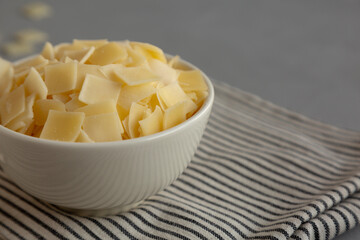 Hard Shaved Parmesan Cheese in a Bowl, side view. Close-up.