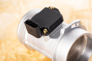 Modern electronic mass air flow sensor on brown paper, close-up. Car spare part, industry