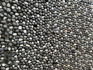 Close-up view of a decorative wall surface covered with a dense, organized layer of small pebble stones.