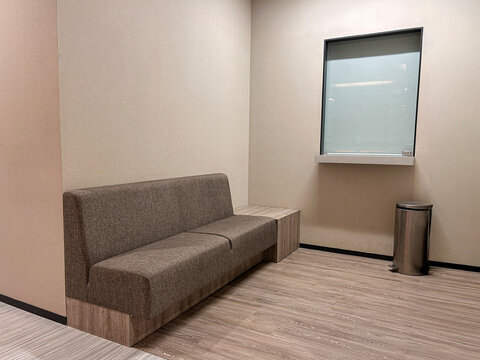 A clean office mailing room featuring a simple brown upholstered bench with a wooden base.