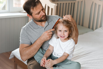 Man brushing daughters hair. Daddy combing girl's hair at home. Responsible good dad braiding his child girl's hair. Handsome father grooming his little one. Morning routine concept. Family life
