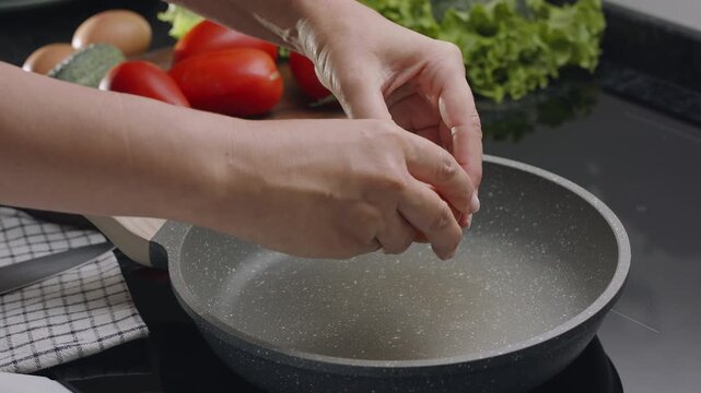 Process of breaking an egg on a frying pan for cooking sunny side up fried egg.
