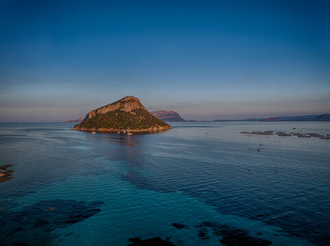 Aerial view of the rugged, verdant Isola di Tavolara rising majestically from the turquoise waters, a jewel of the Mediterranean under a serene sky, Sardinia, Italy.
