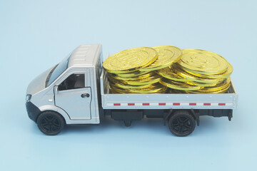 Lorry truck with gold coins on blue background. Shipping and delivery cost, financial fund...