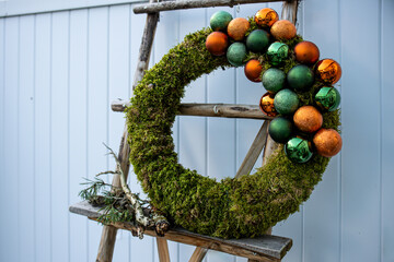 Moss wreath with Christmas baubles standing on rustic ladder