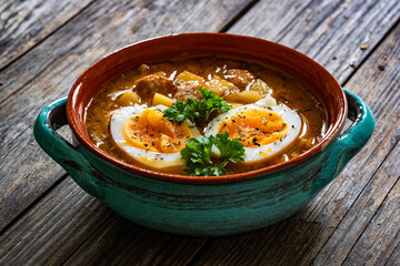 Potato sausage soup with boiled egg on wooden table	