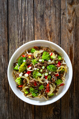 Ground beef and broccoli noodles on wooden table. Top view